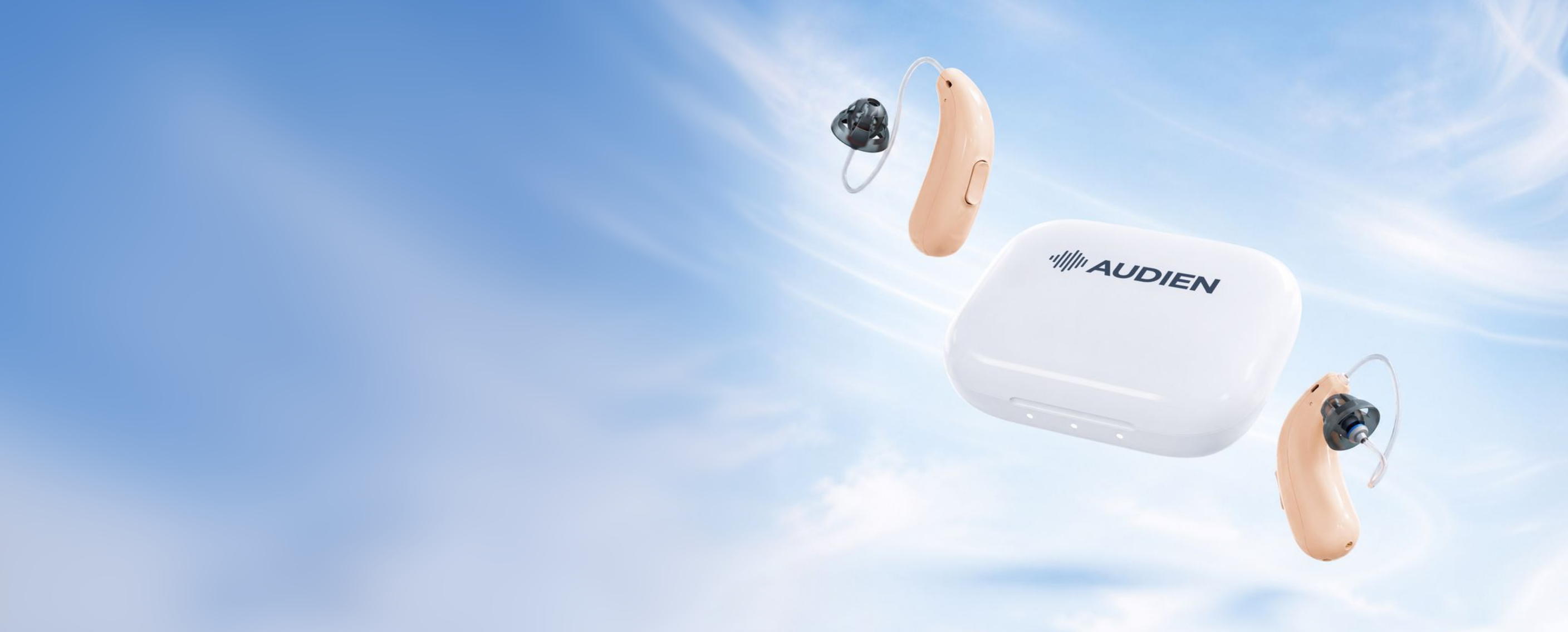 A pair of Audien behind-the-ear hearing devices and their white charging case floating against a bright blue sky with wispy clouds.